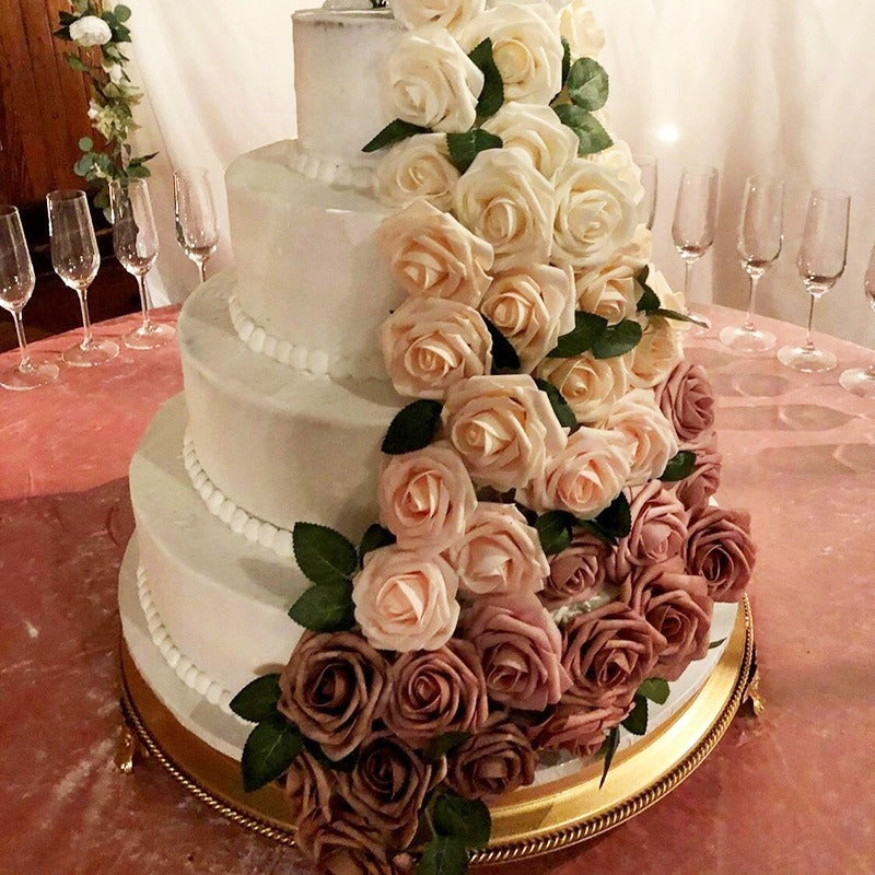 Multi-tiered wedding cake decorated with roses on a table with wine glasses.