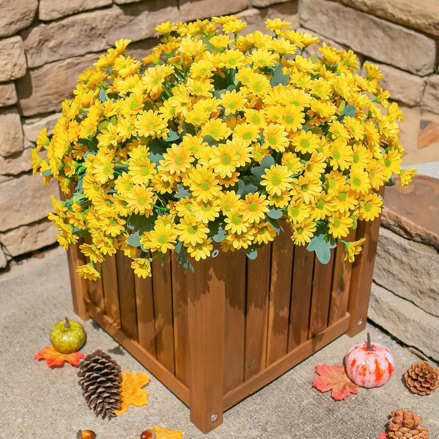 Wooden planter box filled with yellow flowers on a stone surface.