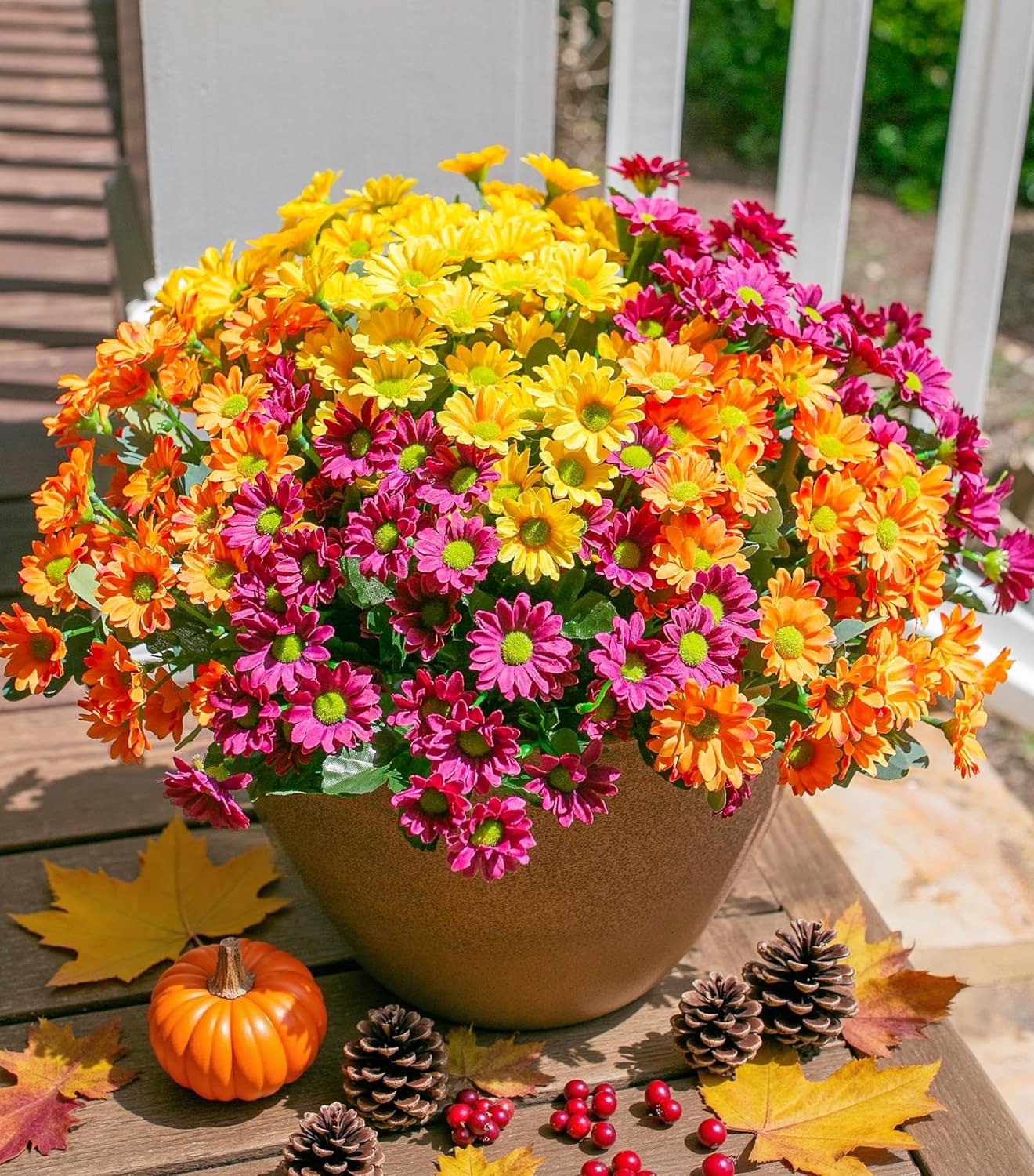 Colorful potted flowers on a wooden surface with autumn decorations.