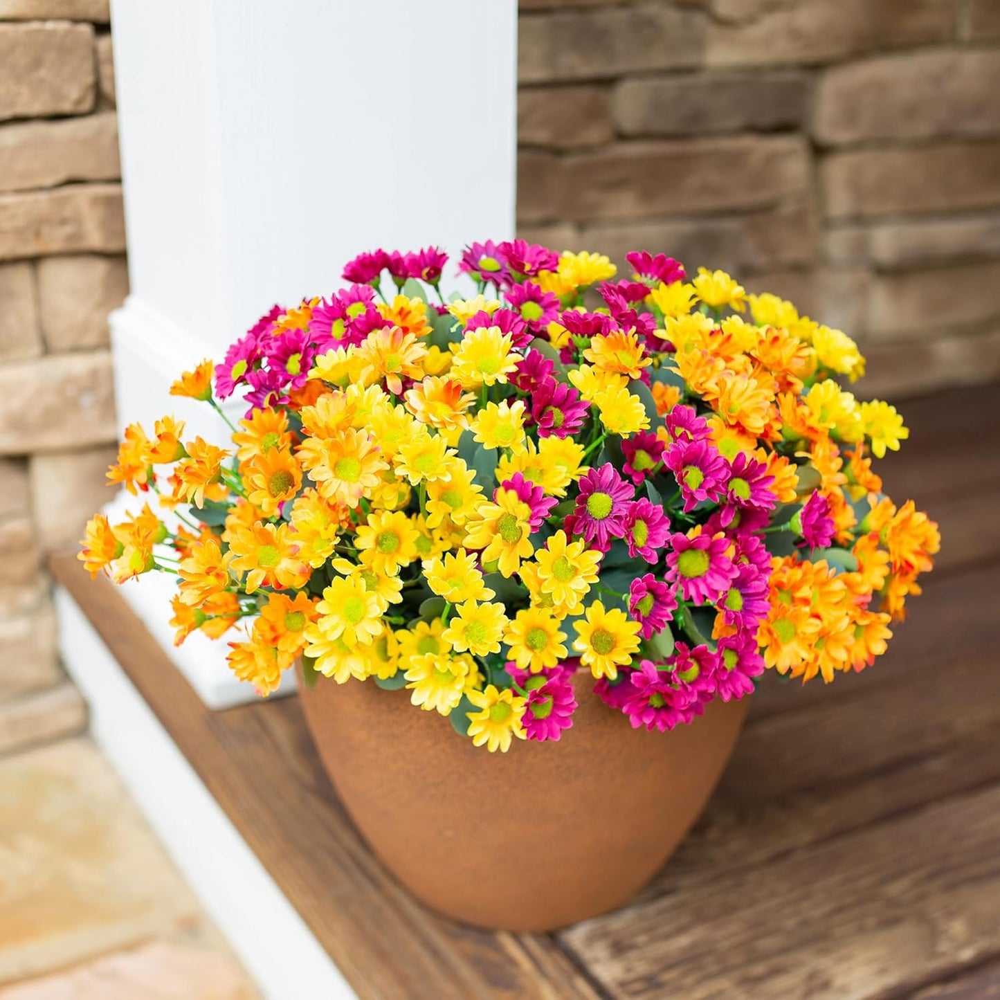 Potted plant with yellow and pink flowers on a wooden surface.