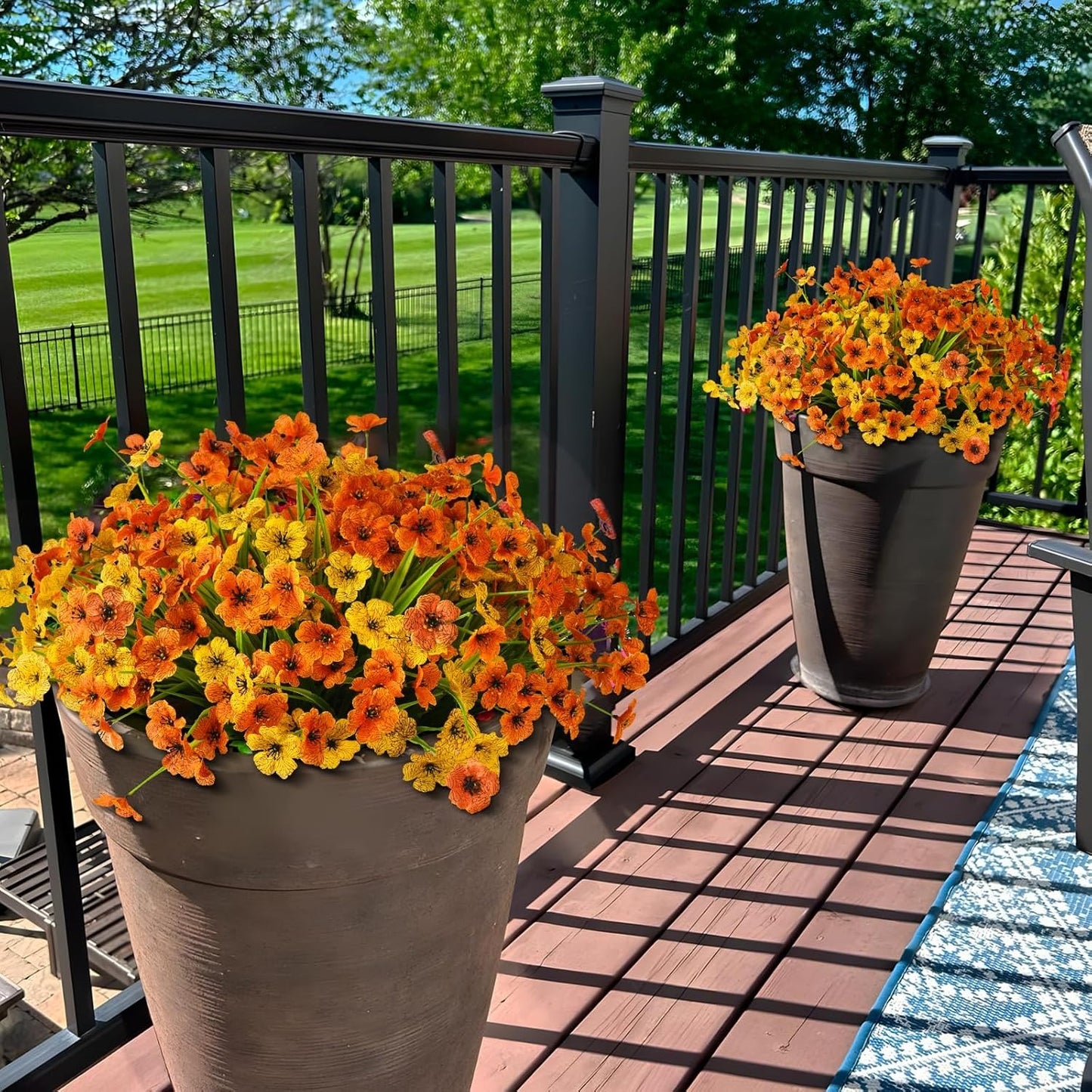 Two potted plants with orange and yellow flowers on a wooden deck.