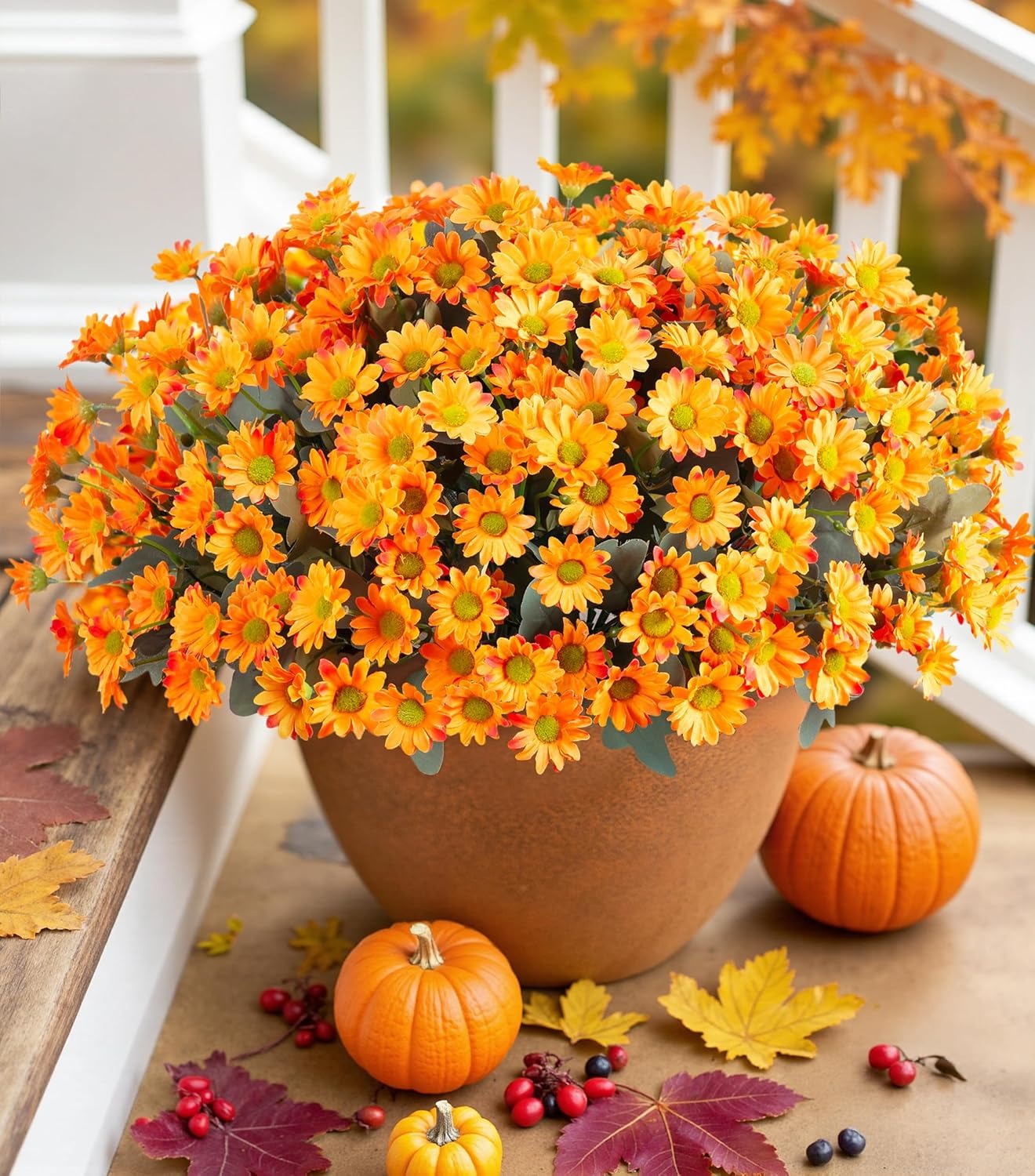Potted plant with orange flowers on a wooden surface with pumpkins and leaves