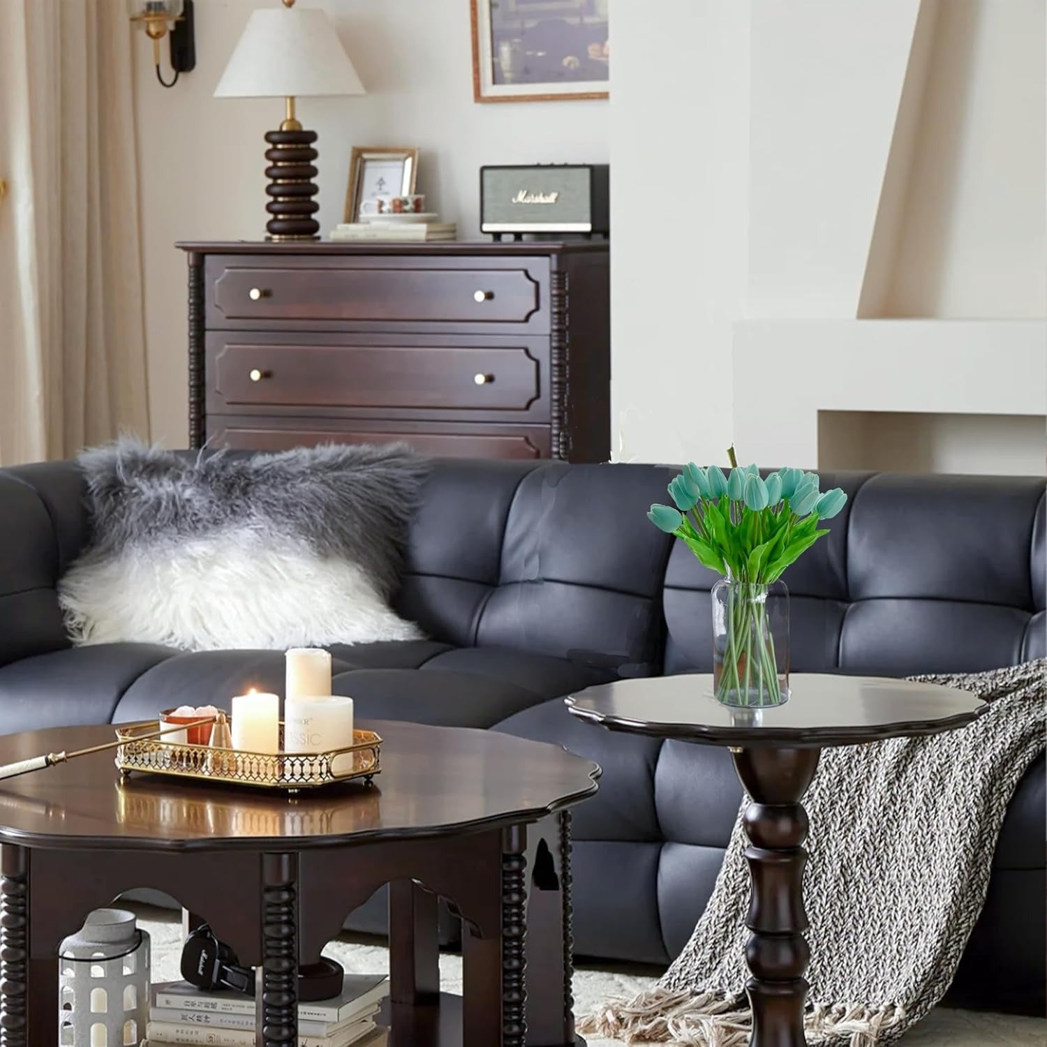 Living room with a black leather sofa, wooden coffee table, and decorative items.