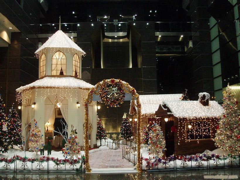 Decorative Christmas scene with a gazebo and gingerbread house in an urban setting.