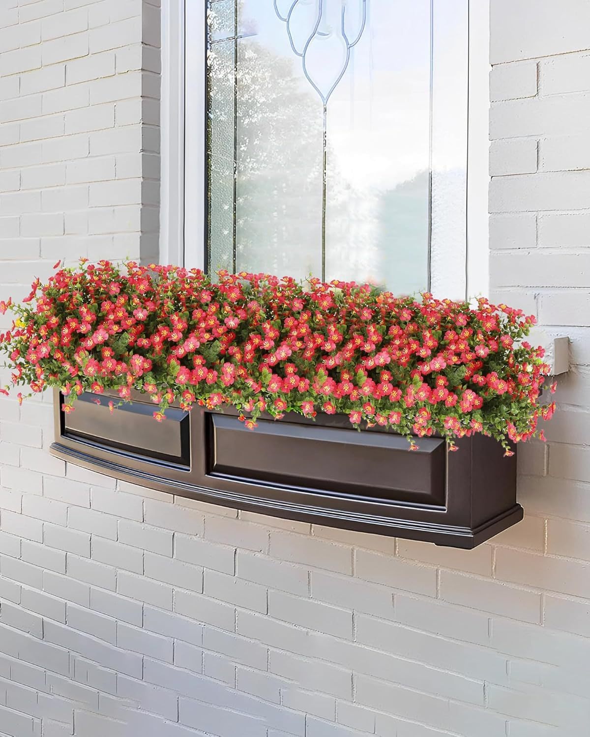 Window box with red flowers on a white brick wall