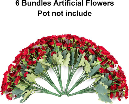 Red artificial flowers arranged in a circular pattern with green leaves on a white background.