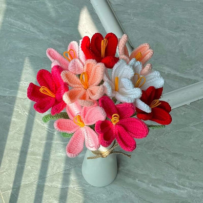 Colorful knitted flowers in a white vase on a light gray surface