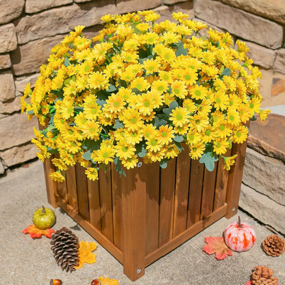 Wooden planter box filled with yellow flowers on a stone surface.